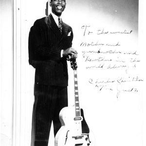 Charlie Christian poses with his guitar and signed a note to his family on this photo.