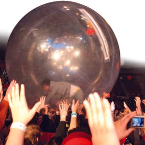 Wayne Coyne of The Flaming Lips rolls around the audience in a giant ball at a live show.