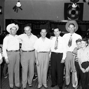Johnnie Lee Wills (in the cowboy hat on the left) and Leon McAuliffe (in the cowboy hat on the right) posing with an unidentified group