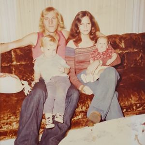 Bryan's dad holding him alongside his mother and younger brother Daniel at his grandparent's home in 1977