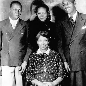 Jazz legend Charlie Christian (on the left) poses for a portrait with his family. It is believed the woman seated is his mother Willie Christian and that the man on the right is his brother Clarence Christian.
