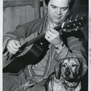 Conway Twitty plays his guitar at home for his dog Tojo.