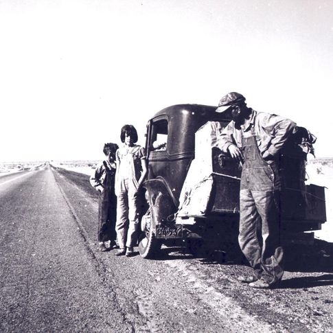 A family lingers on the side of the highway near their car and meager belongings on the great trip west during the 1930s Dust Bowl.