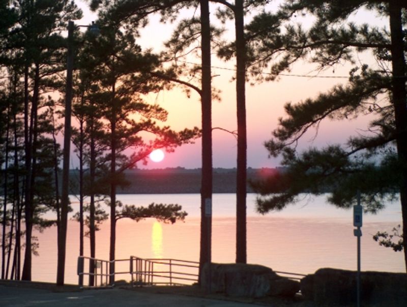 Beautiful pastel shades glow over Potapo Campground at McGee Creek State Park as the sun sinks framed by tall pine trees.