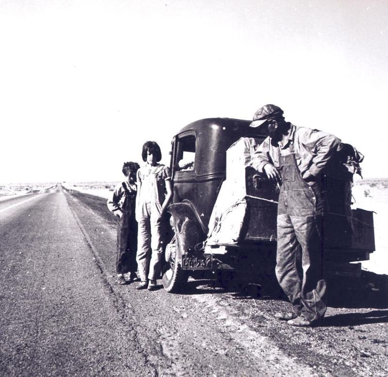 A family lingers on the side of the highway near their car and meager belongings on the great trip west during the 1930s Dust Bowl.