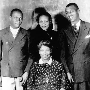 Jazz legend Charlie Christian (on the left) poses for a portrait with his family. It is believed the woman seated is his mother Willie Christian and that the man on the right is his brother Clarence Christian.