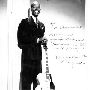 Charlie Christian poses with his guitar and signed a note to his family on this photo.