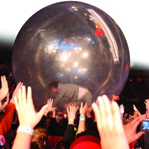 Wayne Coyne of The Flaming Lips rolls around the audience in a giant ball at a live show.